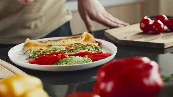 Gros plan des mains du chef méconnaissable garnissant omelette servie avec des légumes frais sur le côté avec de l'herbe verte - Séquence, vidéo