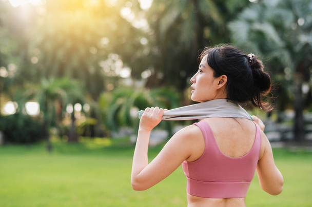 Detailní záběr fit ženské běžkyně jako asijské ženy 30, v růžovém sportovním oblečení, zahřívá po západu slunce běh ve veřejném parku. Přijměte koncept wellness bydlení a přírody. - Fotografie, Obrázek