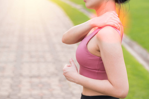 Joggeuse. 30s jeune asiatique femme portant rose vêtements de sport tenant son mal de dos après avoir couru exercice dans le parc public. Concept de douleur dans l'activité. - Photo, image