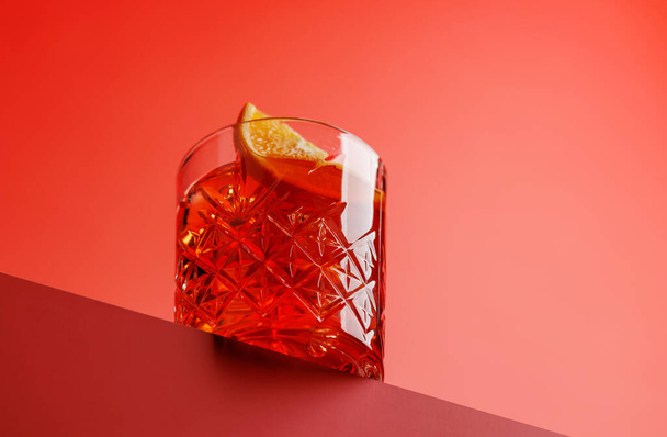 Cocktailgenuss: Klassischer Negroni vor rotem Hintergrund mit Kopierraum - Foto, Bild