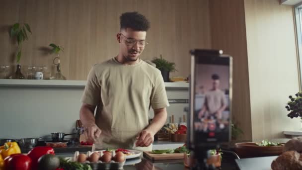 Rack fókusz lövés élelmiszer blogger szolgáló étel tányéron, és bemutatja a kamera közben forgatás főzés vlog telefonnal és állvány beállítás a konyhában - Felvétel, videó
