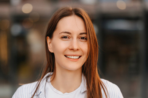 Close up outdoor ritratto femminile di una giovane donna sorridente che indossa camicia bianca. - Foto, immagini