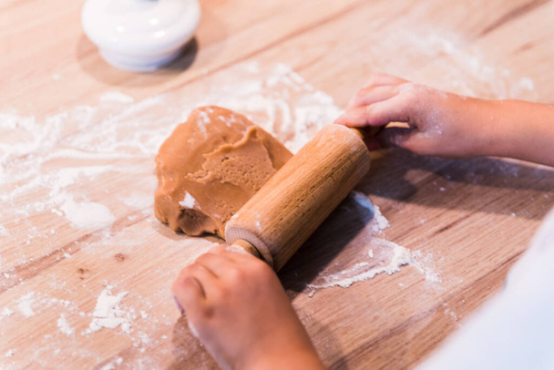 Feche mãos que amassam uma massa de farinha na mesa de madeira. - Foto, Imagem