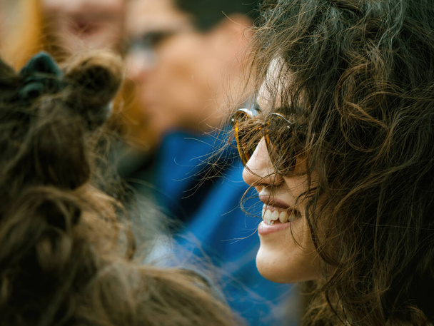 Strasbourg, France - Mar 29, 2023: A side view of a smiling city-dwelling woman wearing sunglasses in the bustling urban environment - 写真・画像
