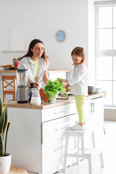 小さな女の子とともに彼女のお母さん調理健康サラダでキッチン - 写真・画像