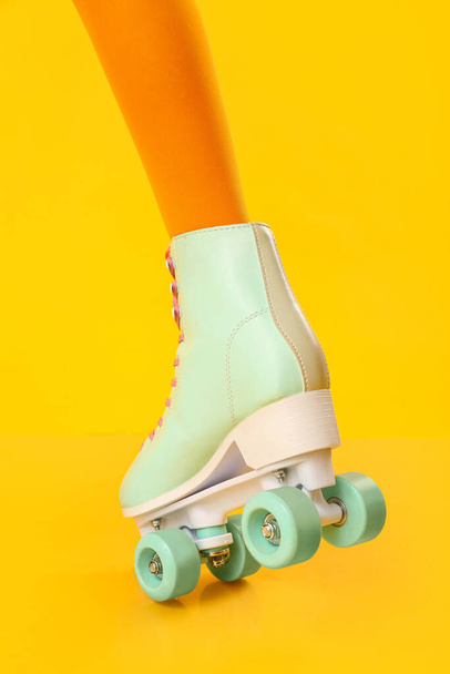 Leg of woman in roller skates on yellow background - Photo, Image
