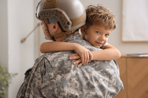 Μικρό αγόρι αγκαλιάζει τον στρατιωτικό πατέρα του στο σπίτι, κοντινό πλάνο - Φωτογραφία, εικόνα