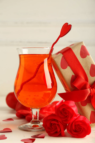 Bir bardak nefis kokteyl, içinde kalpler, güller ve ışık masasında hediye, yakın plan. Sevgililer Günü kutlaması - Fotoğraf, Görsel