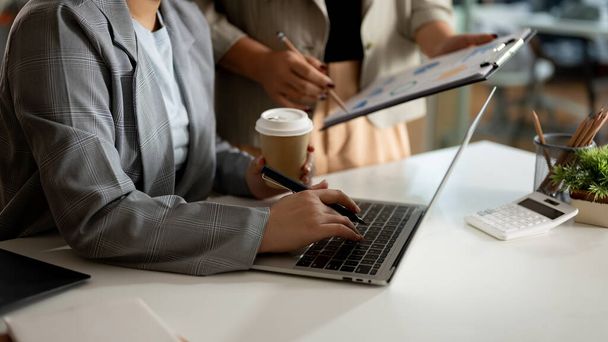 Снимок бизнесвумен, работающей над ноутбуком и мозговой штурм работы с коллегой в офисе. Концепция встреч предпринимателей - Фото, изображение