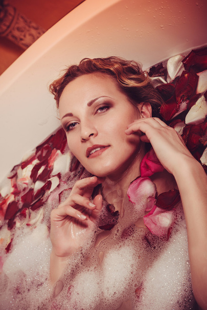 Mladá žena s červenými vlasy si perličková koupel s svíčka. - Fotografie, Obrázek