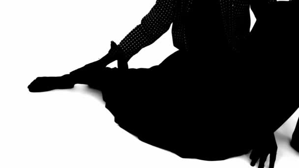 Sziluett egy ülő személy egy áramló ruha egyik lábát kiterjesztett, elszigetelt fehér alapon. - Felvétel, videó