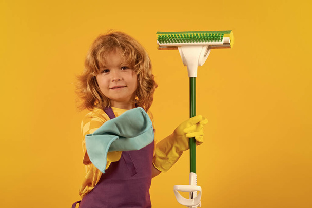 Dziecko robi prace domowe. Dzieci pomagające w sprzątaniu domu. Pokojówka w domu. słodkie dziecko chłopiec pomaga w sprzątaniu na żółty studio backdround - Zdjęcie, obraz