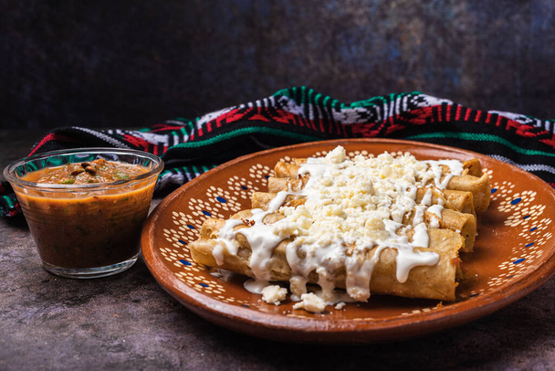 メキシコの泥料理でクリームとチーズを添えたフライドポテトタコス. タコス・ドロドス,メキシコ料理. - 写真・画像