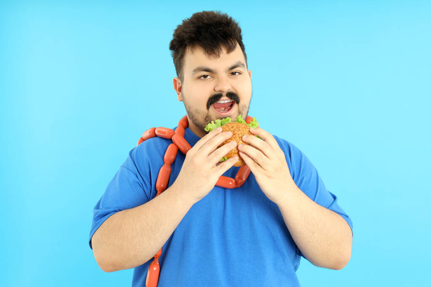 Nadváha muž s jídlem na modrém pozadí. - Fotografie, Obrázek