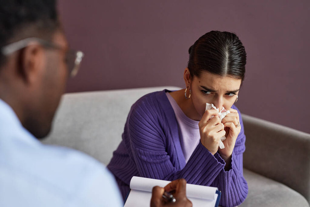 Genç bir kadın terapistle konuşurken ağlıyor ve burnunu siliyor. - Fotoğraf, Görsel