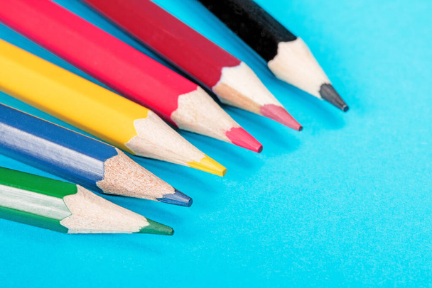 Ζωηρά πολύχρωμα μολύβια τοποθετημένα σε σχήμα ανεμιστήρα σε μπλε φόντο. Τα μολύβια είναι τακτοποιημένα και δημιουργούν μια οπτικά ελκυστική και ομαλή σύνθεση. - Φωτογραφία, εικόνα