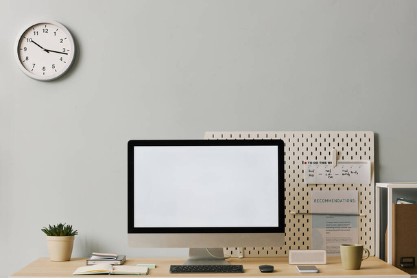 Imagem de fundo do computador com tela branca em branco na mesa na configuração mínima do escritório em casa com relógio analógico na parede pastel - Foto, Imagem