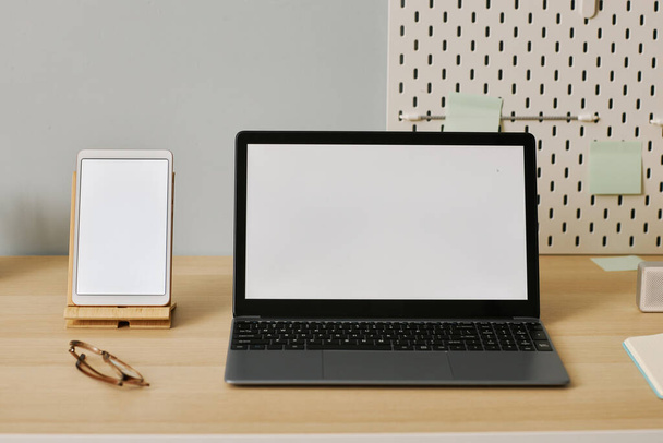 Imagen de fondo del portátil abierto con maqueta de pantalla blanca en el escritorio en el lugar de trabajo - Foto, Imagen