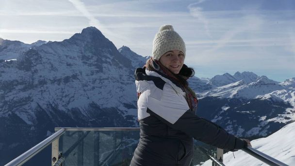 Портрет жінки, що стоїть на знаковій платформі Перший пік Гріндельвальда з видом Приголомшлива альпійська панорама, одягнена в зимовий одяг і посміхається на камеру - Фото, зображення