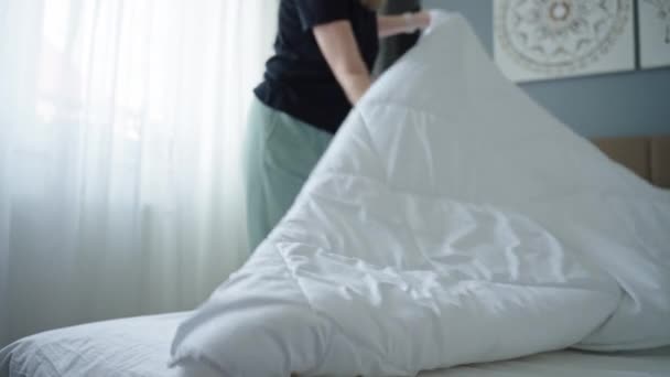 Vrouw vervangt beddengoed in de kamer. Vrouwelijk opmaken van bed in de slaapkamer. Routine klusjes en huishoudelijk werk - Video