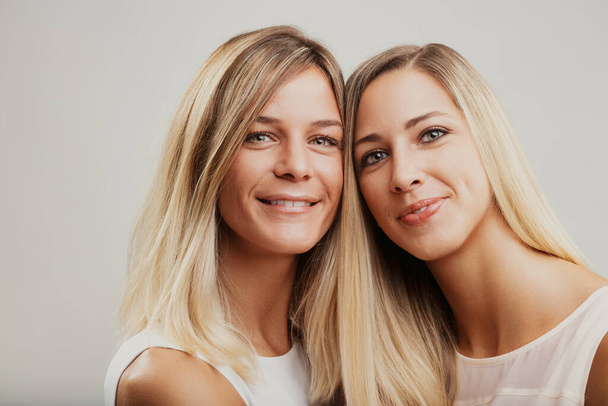 Blonďaté ženy, možná sourozenci, sdílejí veselý okamžik, láskyplně zabalené v objetí - Fotografie, Obrázek