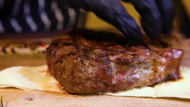 Ein behandschuhter Kellner schneidet ein saftiges Steak auf. Ein Restaurantkoch schneidet ein mittelseltenes Rindersteak. - Filmmaterial, Video