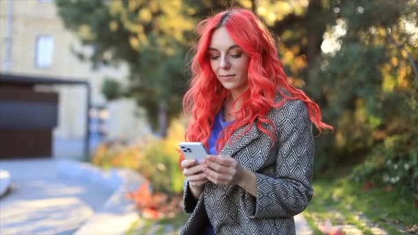 Mladé červené vlasy podnikání sebevědomá žena pomocí chytrého telefonu venkovní z města západ slunce pozadí.  - Záběry, video