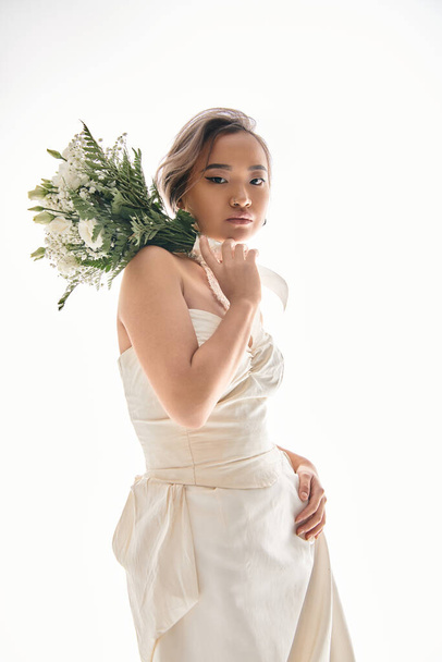 attractive asian girl in her 20s with grace makeup holding on shoulder white flowers bouquet - Φωτογραφία, εικόνα