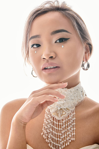 portrait of attractive asian woman with elegant  makeup posing with hand on chin - Фото, изображение