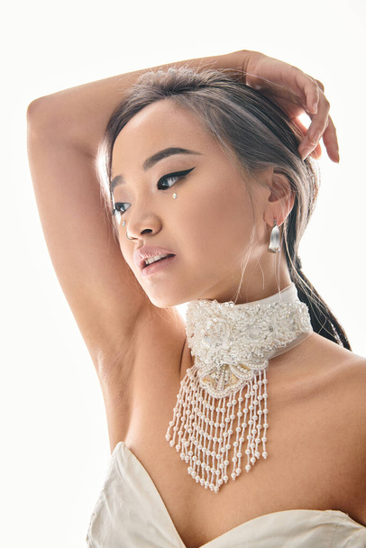 profile of elegant asian young woman with grace makeup looking to side and putting hands behind head - Foto, afbeelding