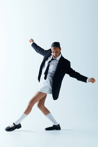 A young black woman in a stylish suit and tie joyfully dancing in a studio. - Photo, Image