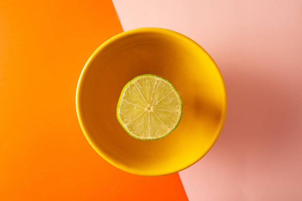Çift renkte dilimlenmiş limon. Pembe ve turuncu geometrik arka plan. Sarı bir kase içinde. - Fotoğraf, Görsel