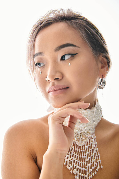 portrait of graceful asian woman with elegant makeup looking to camera and touching chin with hand - Fotografie, Obrázek