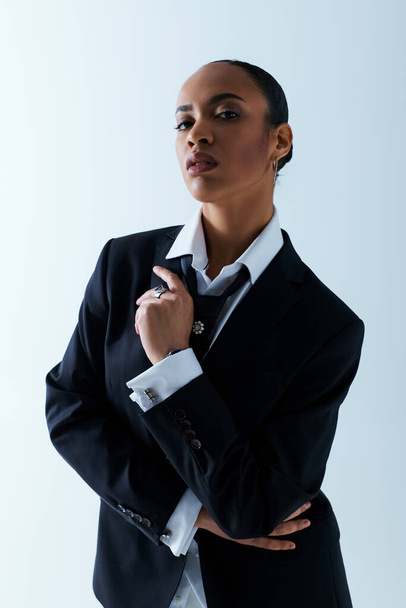 Een jonge Afro-Amerikaanse vrouw in de twintig, gekleed in een zakenpak, slaat een pose aan. - Foto, afbeelding