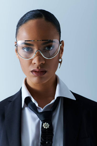 Młoda Afroamerykanka w wieku 20 lat, pewnie ubrana w garnitur, krawat, okulary w studio. - Zdjęcie, obraz
