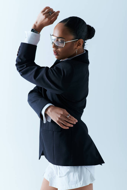 Молода афроамериканка, одягнена в костюм і окуляри, вражає позу в студії - Фото, зображення