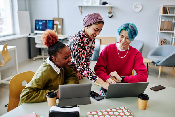 Grupo diverso de jovens criativos que usam o computador portátil durante a reunião no escritório e sorrindo alegremente - Foto, Imagem