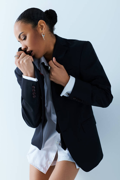Μια νεαρή Αφρο-Αμερικανίδα αποπνέει εμπιστοσύνη στο κοστούμι και τη γραβάτα σε ένα στούντιο.. - Φωτογραφία, εικόνα