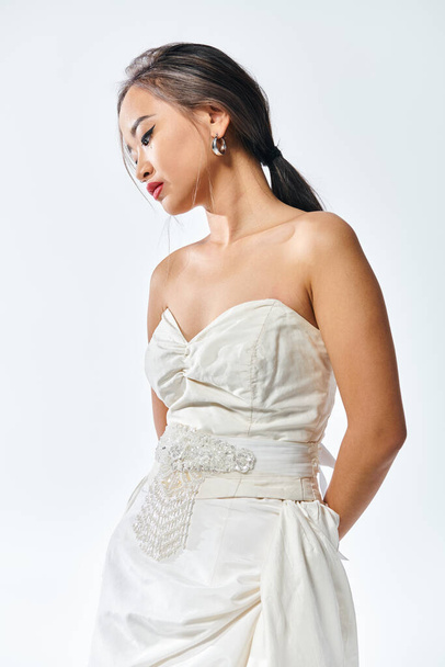 Kırmızı dudaklı ve inci kolyeli beyaz elbiseli zarif Asyalı genç kadın. - Fotoğraf, Görsel
