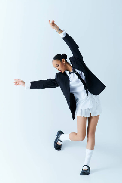 Молода афроамериканка, одягнена в костюм і спідницю, витончено танцює в студії - Фото, зображення