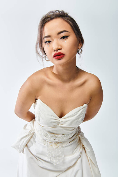 beautiful asian woman in her 20s with red lipstick leaning to forward on white background - Фото, зображення