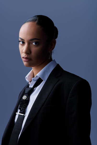 Eine stilvolle junge Afroamerikanerin posiert selbstbewusst in Anzug und Krawatte. - Foto, Bild