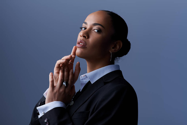 Uma jovem afro-americana em um terno de negócios elegantemente mantém as mãos juntas. - Foto, Imagem
