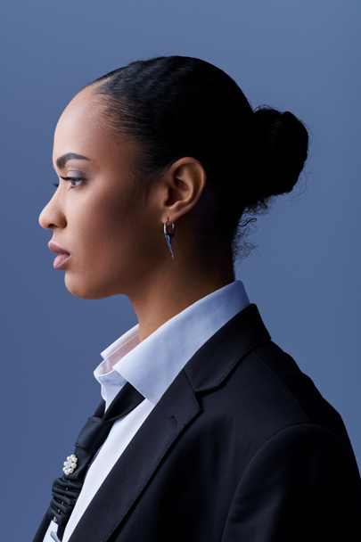 Νεαρή Αφρο-Αμερικανίδα με κοστούμι και γραβάτα ατενίζει με προσοχή το πλάι.. - Φωτογραφία, εικόνα