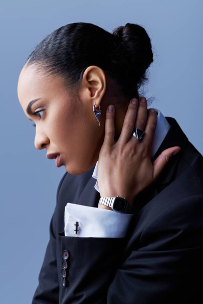 Una joven afroamericana con un traje elegante, escuchando atentamente con la mano al oído. - Foto, imagen