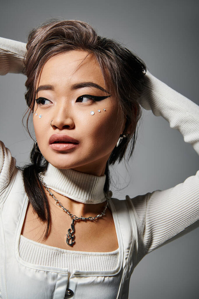 portrait of asian woman with daring makeup putting hand behind head and looking to down - Foto, Imagem