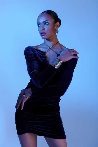 A young African American woman strikes a pose in a black dress for a glamorous portrait. - Photo, Image
