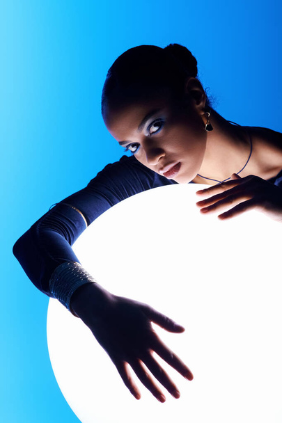 A young African American woman places her hands on a mystical, glowing orb. - Photo, Image