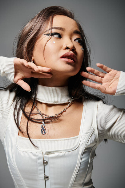 portrait of charming asian woman with heavy makeup posing with hands against grey background - Photo, Image