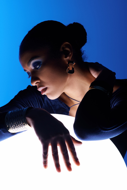 Une jeune Afro-Américaine pose délicatement ses mains sur un objet lumineux - Photo, image